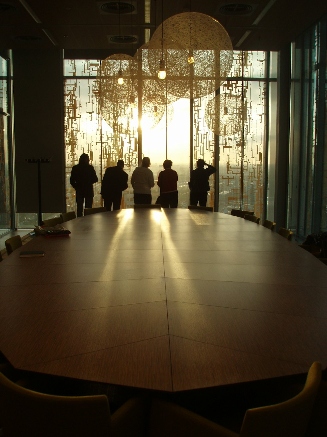 Five people stand by a window overlooking a city skyline.