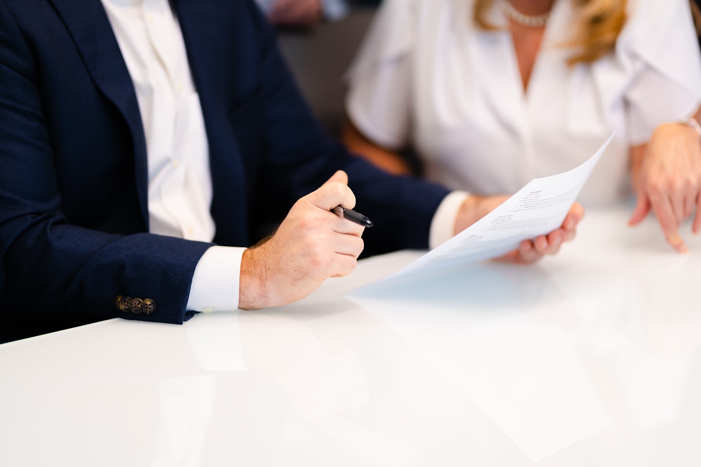 Man and woman reviewing document at white table.