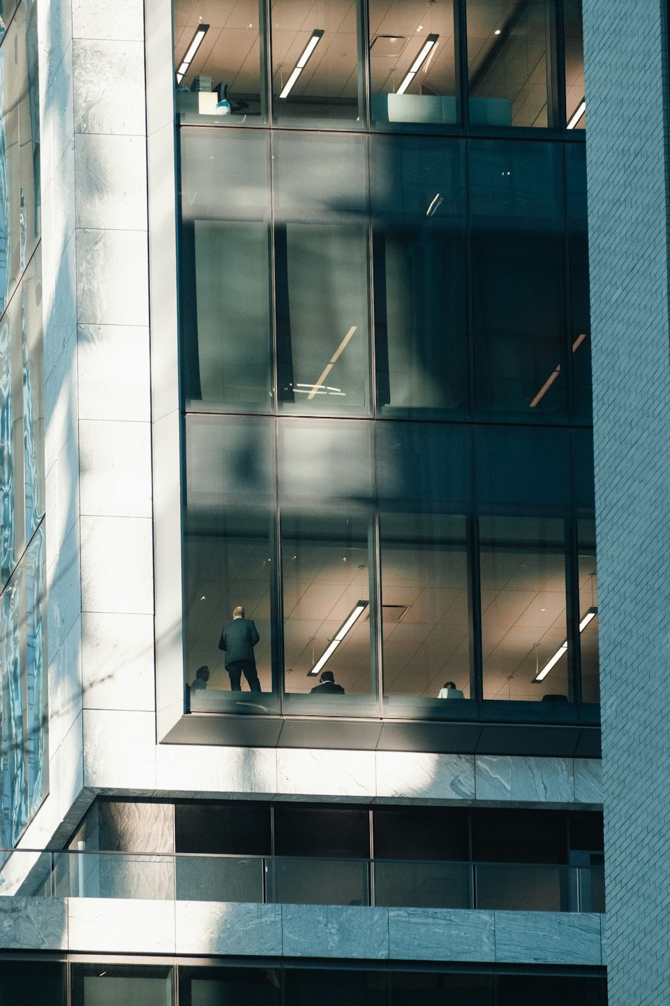 Man in a suit standing by a modern office window.