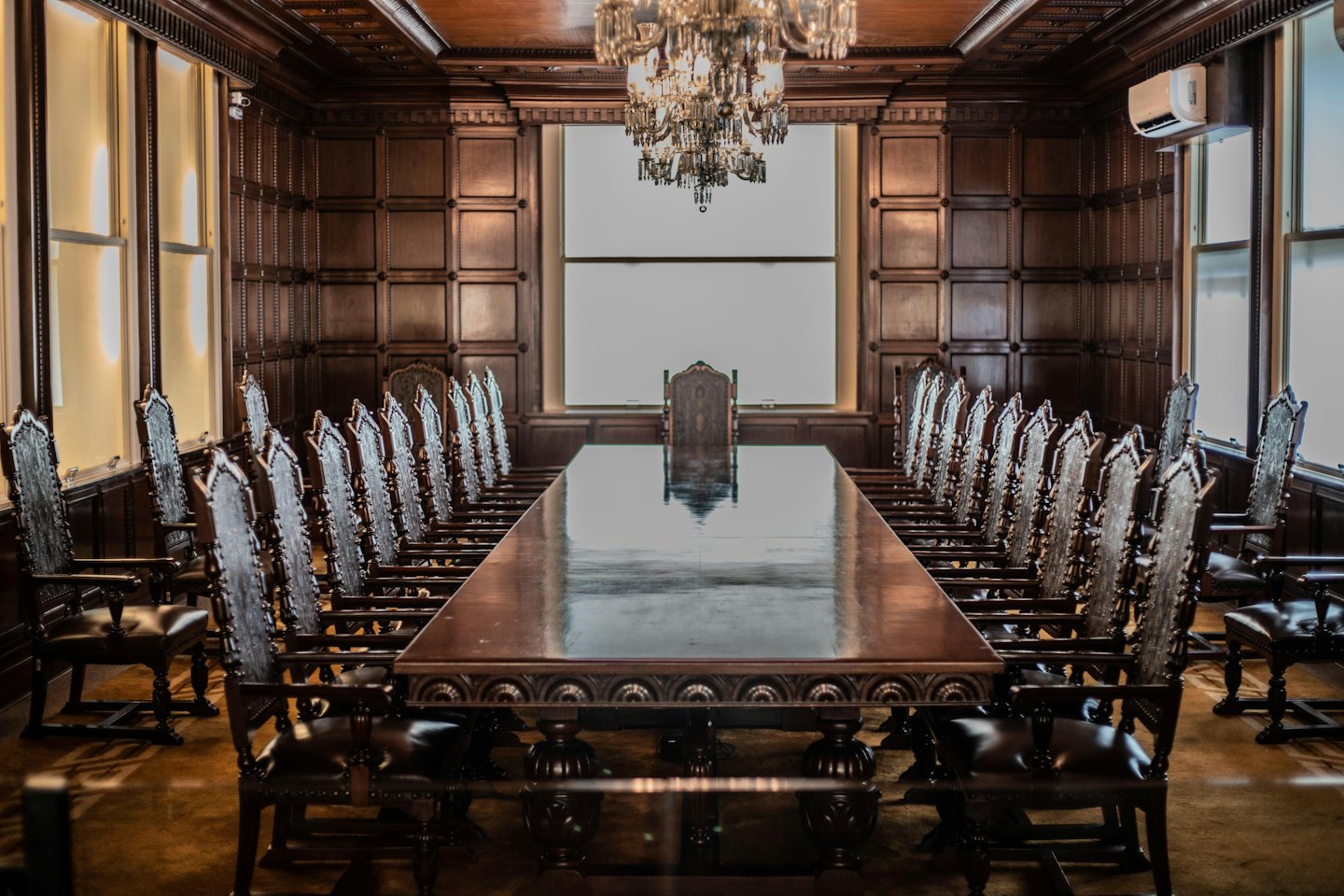 Empty upscale boardroom with dark wood table and chairs.