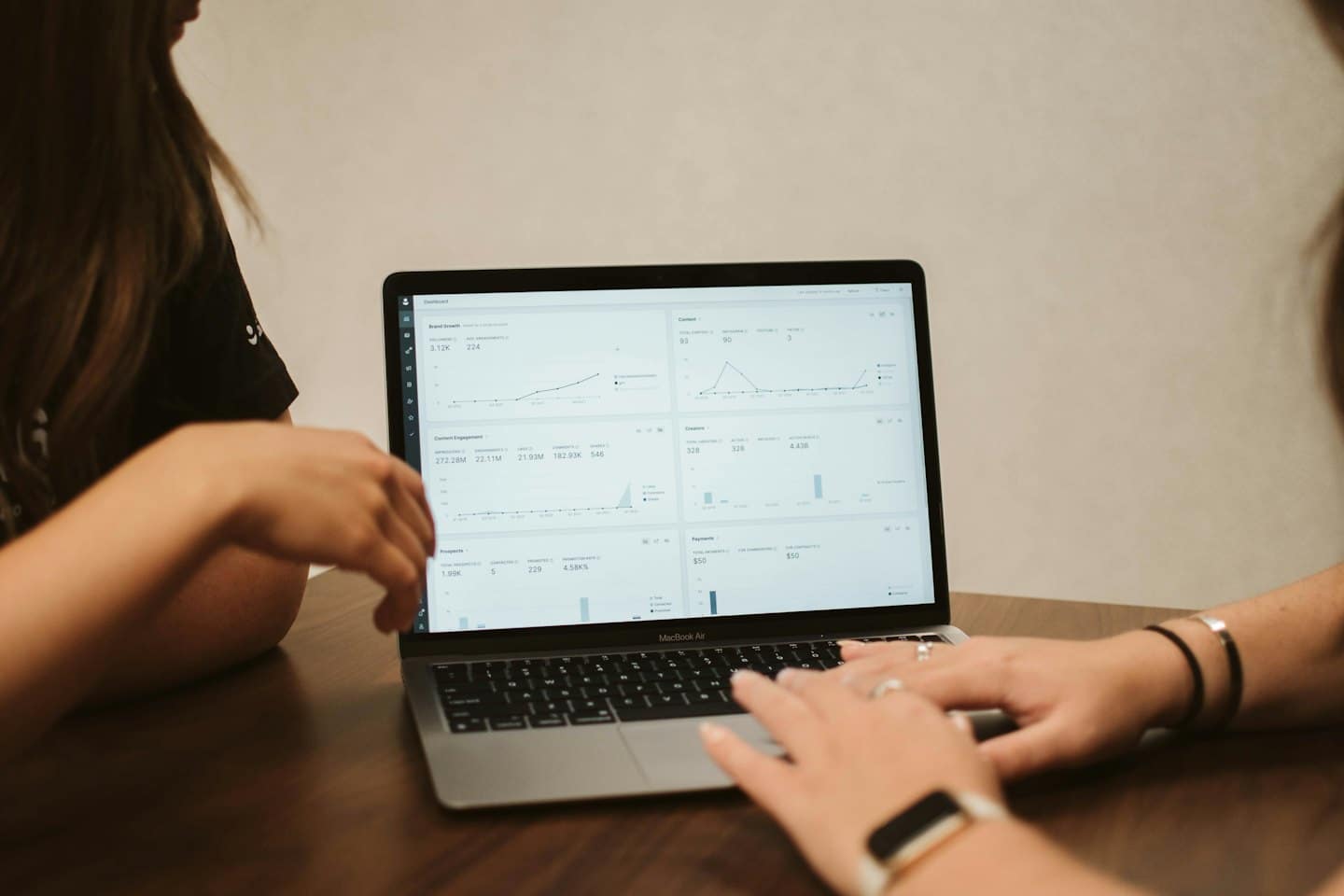Two people collaborating over business data on a MacBook.